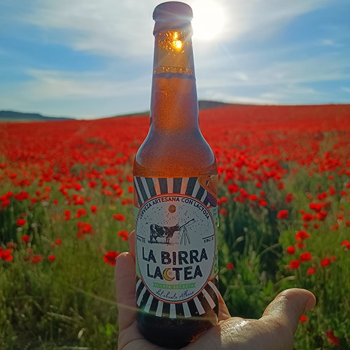 Botella de La Birra Láctea en un campo de amapolas sobre una mano